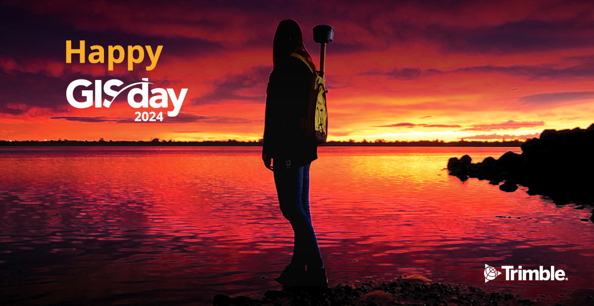 GIS Day 2024 image showing a vivid sunrise over water with a GIS user in foreground