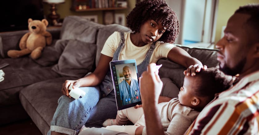 A family sitting on a couch conducting a telehealth visit