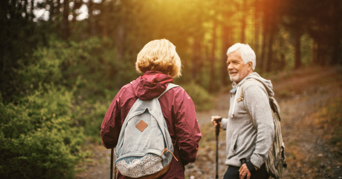 An older man and woman hiking in the woods