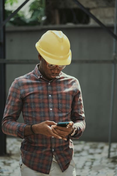 A young construction worker enters data into a mobile device in the field