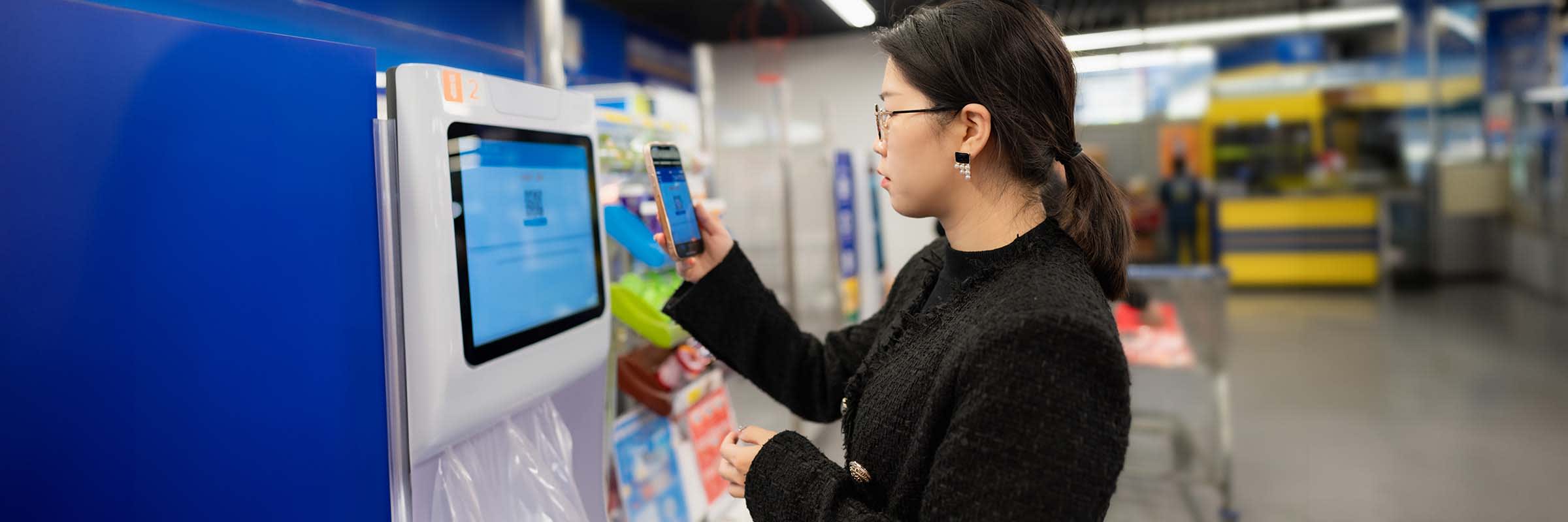 A shopper uses the CPROMO phone app to scan a QR code which will allow her to obtain her complimentary bags from the dispensing machines.