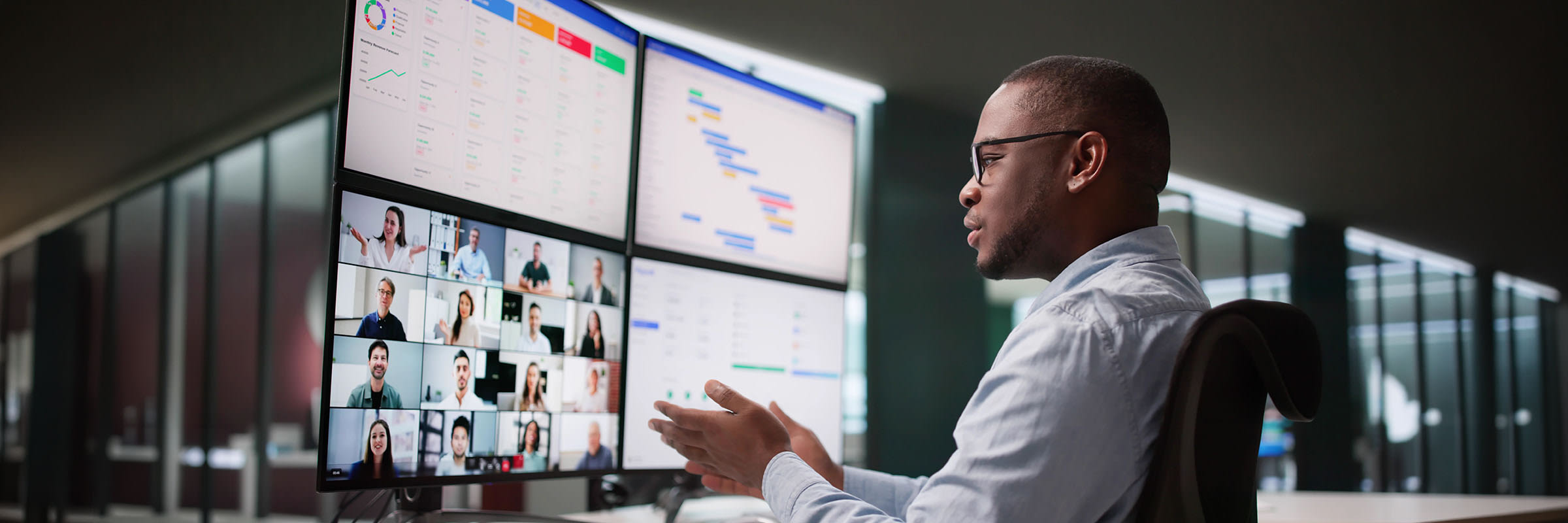 Person looking at a large monitor split into four quadrants: a Zoom meeting, calendar, topic insights and a GANTT chart. 