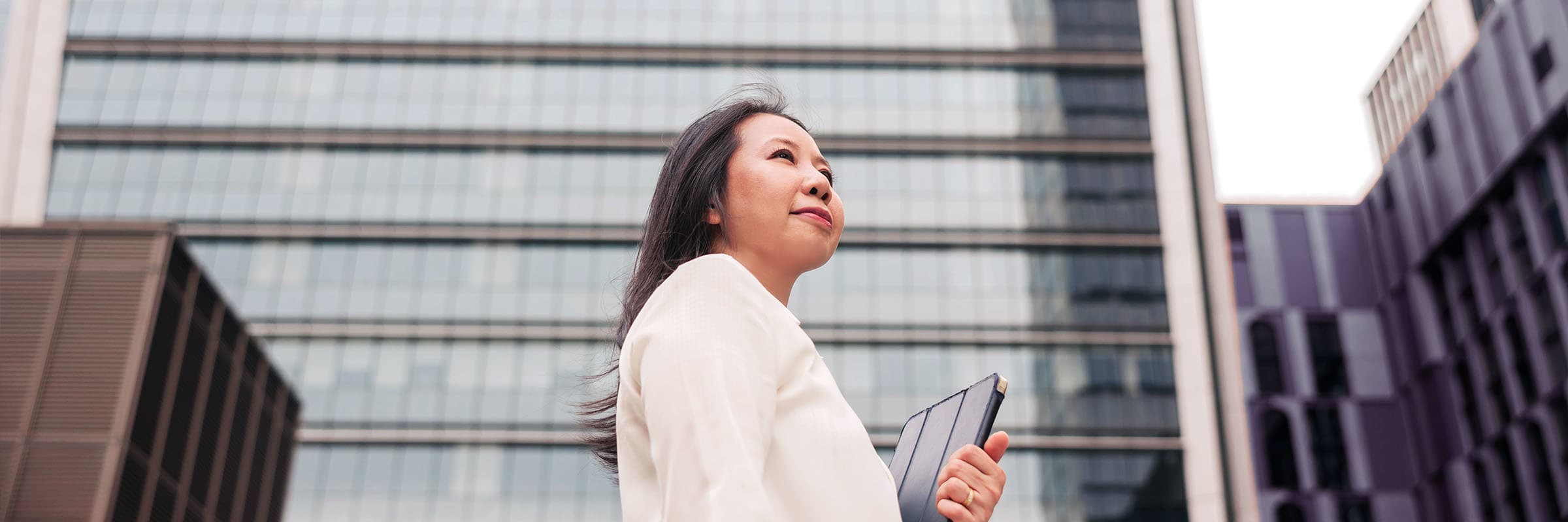 Lady in front of a building holding a tablet connected to Bell's 5G mobile network.