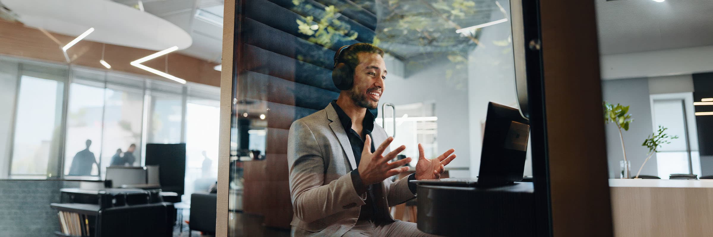 A man on a conference call, looking at his PC with hands raised during the conversation