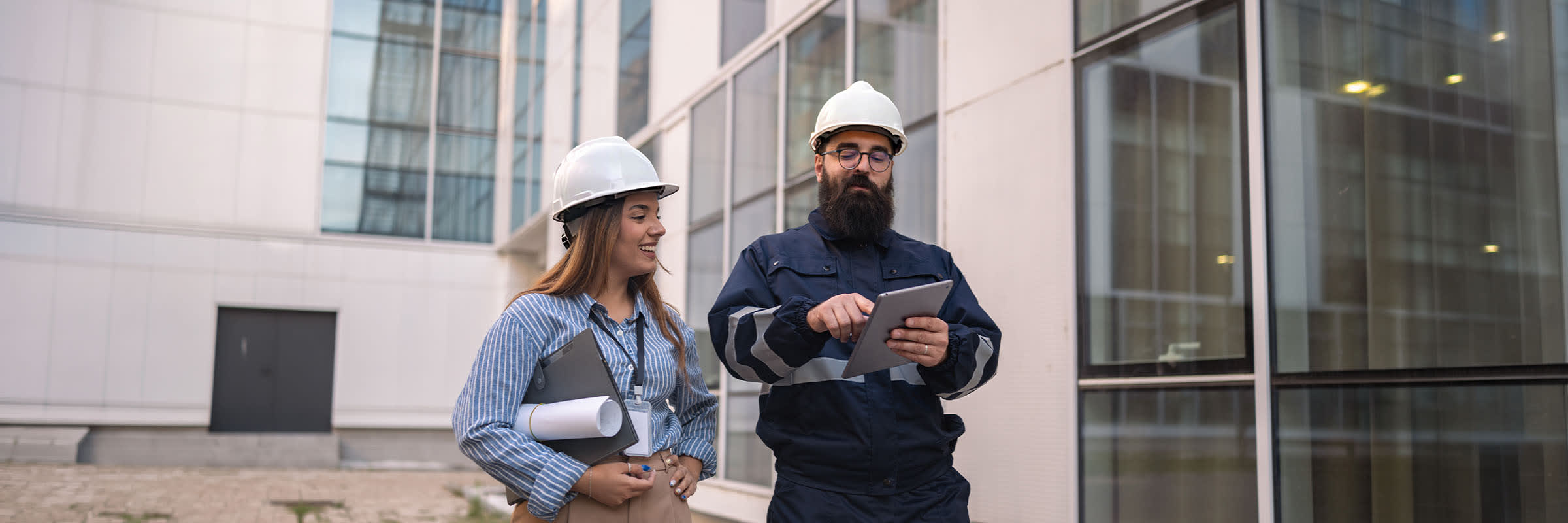 Deux techniciens de chantier portant des casques de s&eacute;curit&eacute; et consultant des donn&eacute;es op&eacute;rationnelles sur une tablette 