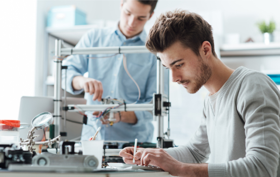 Engineering students working in the lab, a student is using a 3D printer in the background