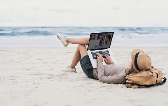 Girl working on laptop computer on a beach. Freelance business concept