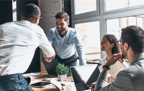 Young modern men in smart casual wear shaking hands and smiling while working in the creative office