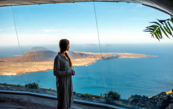 Woman looking on Graciosa island from El Rio viewpoint on Lanzarote island in Spain