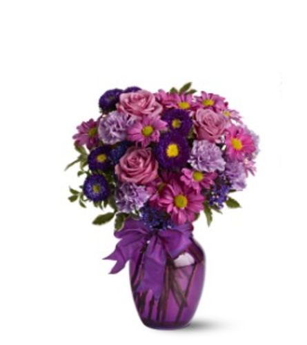 ASSORTED PURPLE FLOWERS ARRANGED LOOSE & AIRY IN A VASE