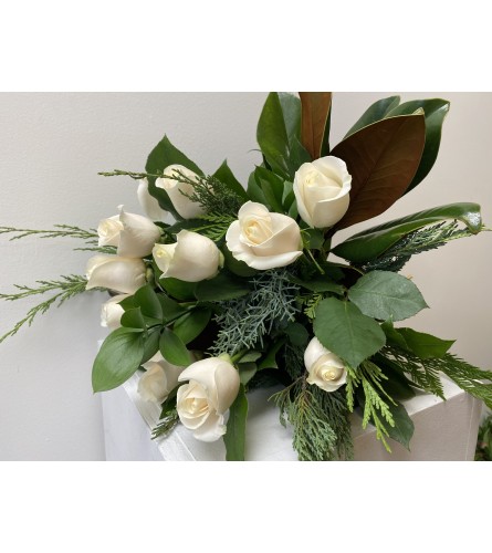12 White roses with magnolia leaves. An arrangement by Flower Trends Florists.