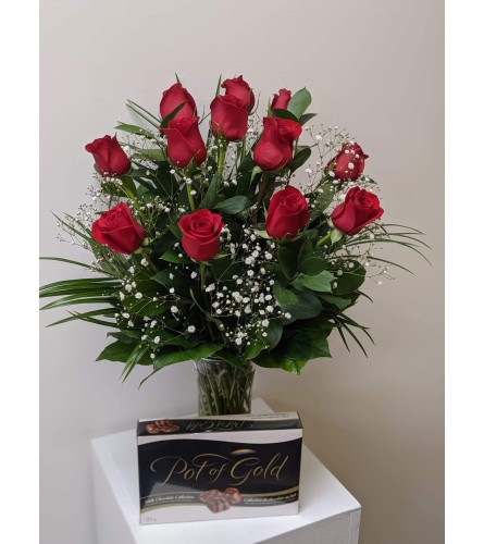 12 Classic Red roses arranged in a vase with a box of chocolates.