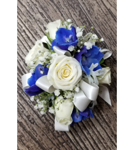 Wedding or prom spray rose and blue delphinium wrist corsage. An arrangement by Timp Valley Floral.