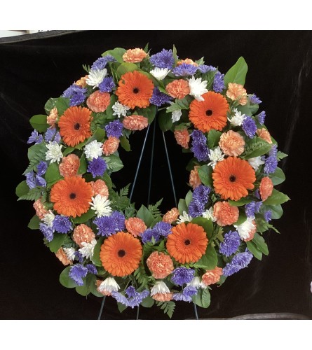 Blue and Orange Wreath. An arrangement by Roma Flowers and Gifts.