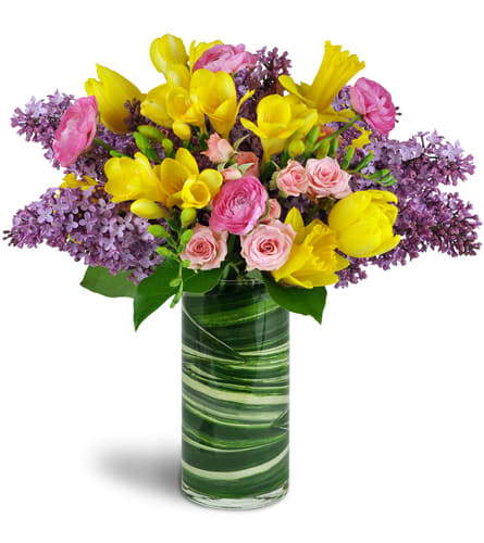 Spring Smiles™. An arrangement by A Touch of Class Flowers and Drapery. Lilacs, tulips, and more are gorgeously arranged in a glass vase..