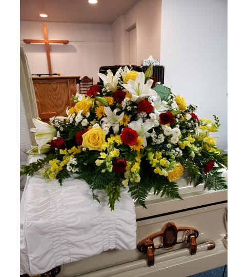 Lily and Sunshine casket Spray. An arrangement by Flowers By Fiore.