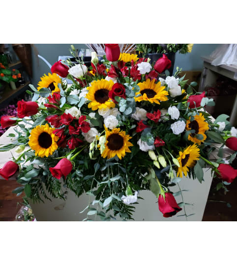 Glorious Sunflowers and Red Roses Casket Spray. An arrangement by Flowers By Fiore.
