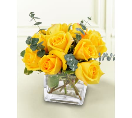 DOZEN YELLOW ROSES DENSELY ARRANGED IN LOW VASE