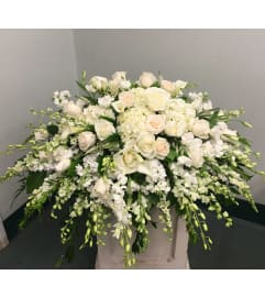 Casket Spray of white roses, orchids, etc.. An arrangement by Renton Flower Shop.