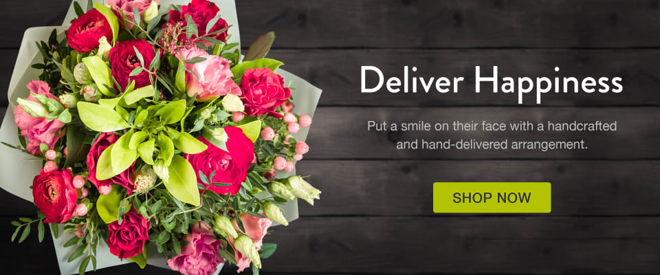 Lime green and pink roses and berries in a wrapped bouquet on a dark wood background - flower delivery in Mamaroneck