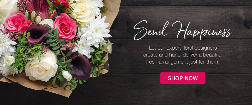 Vibrant pink roses, calla lilies, and white flowers in a wrapped bouquet on a dark wood surface - flower delivery in Ainslie Wood, Hamilton