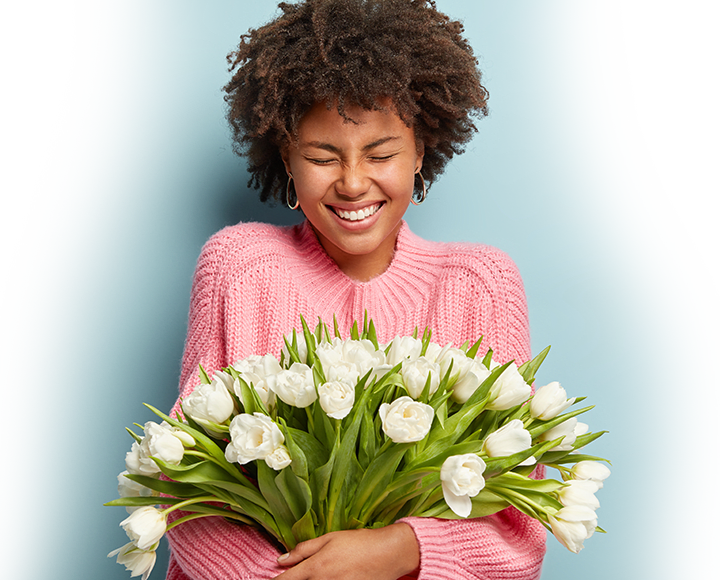 A woman smiling and holding flowers