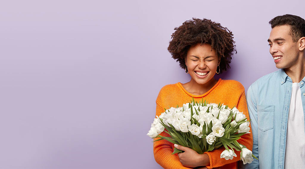 A woman holding flowers and standing next to a man