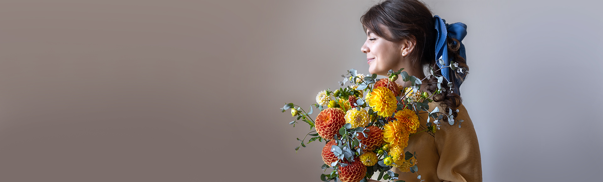 A woman holding a warm, autumnal bouquet