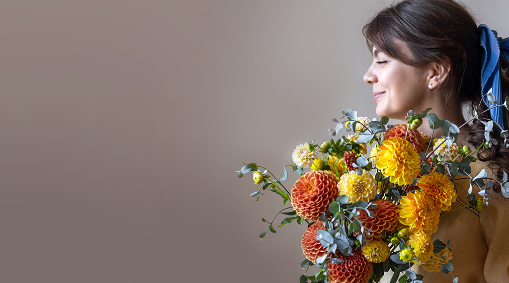 A woman holding a warm, autumnal bouquet
