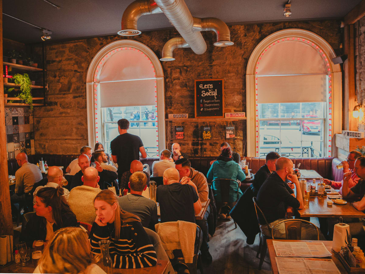 Packed dining room with arched windows and exposed stone at Burgers and Beers Grillhouse, Edinburgh