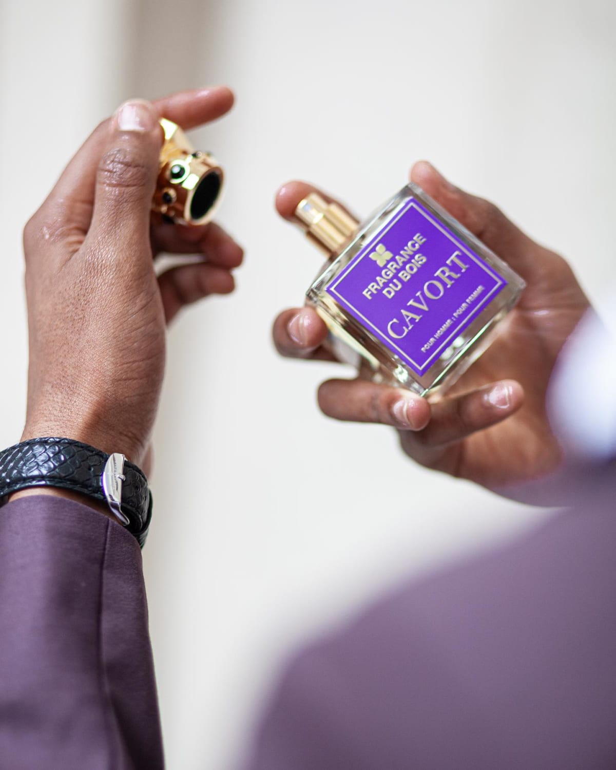 Hands uncapping a Fragrance Du Bois Cavort perfume bottle with a gold jewelled cap