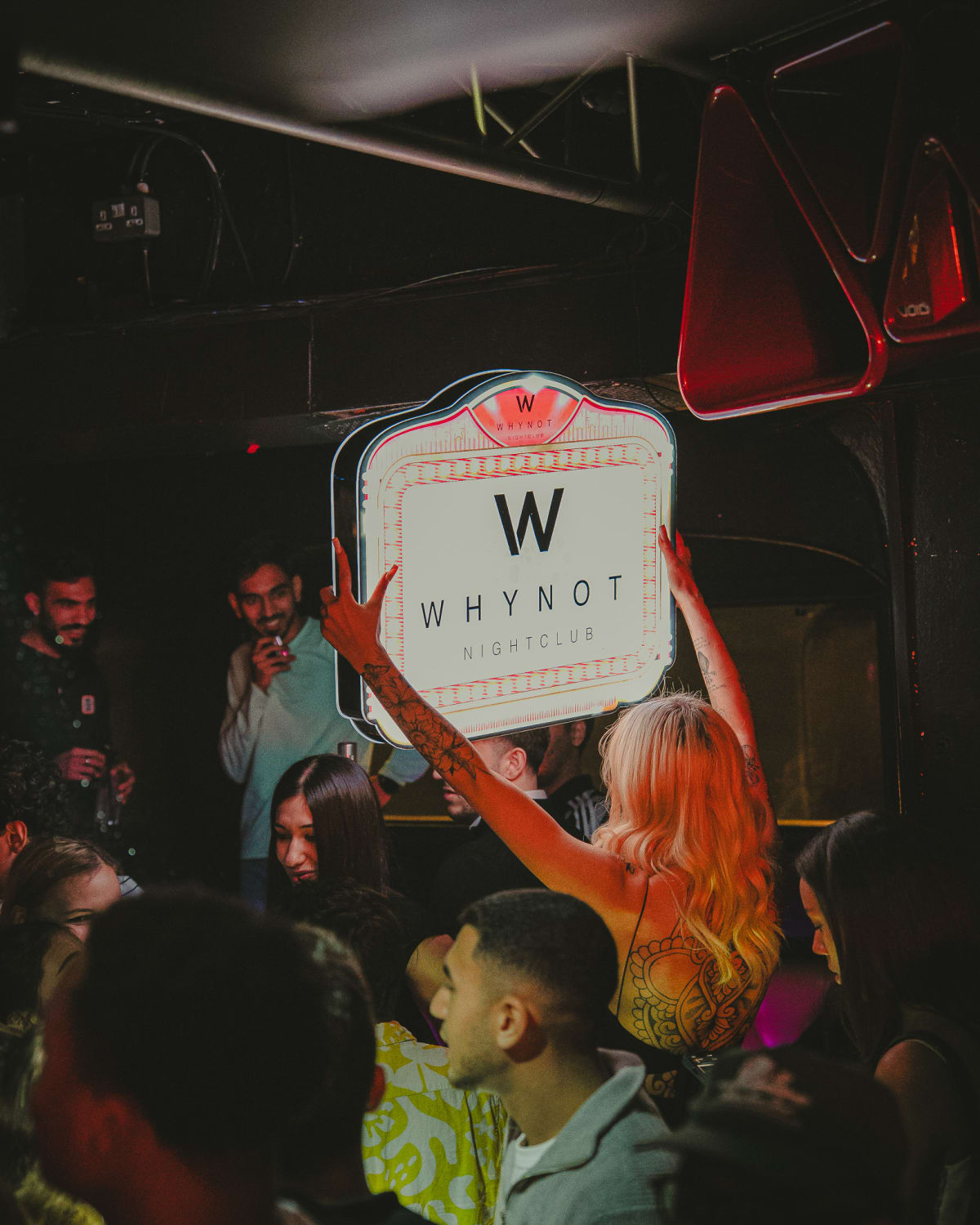 Guests socialising on the covered terrace at Why Not Nightclub