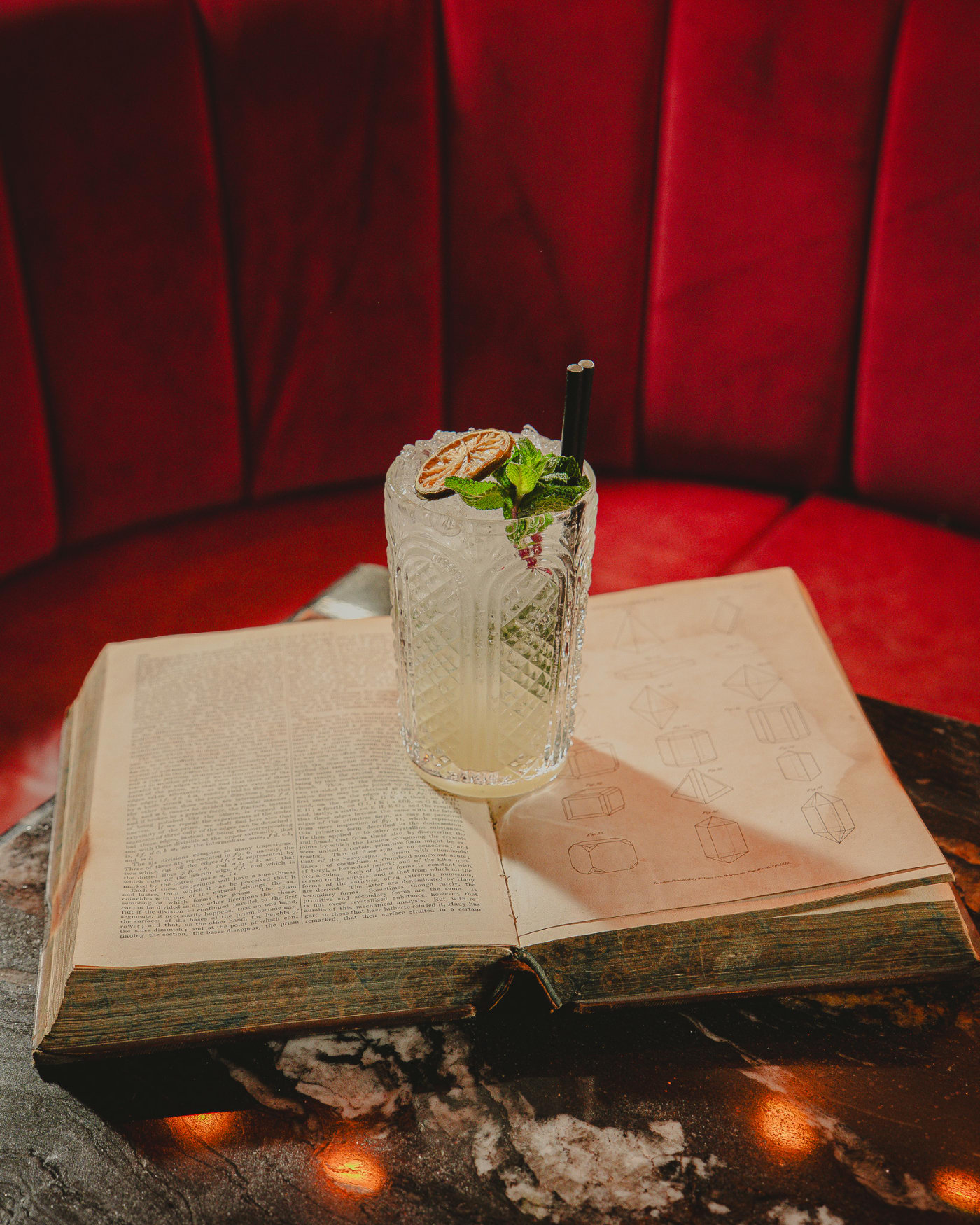 Mojito resting on an open vintage book at Jackson The Tailor