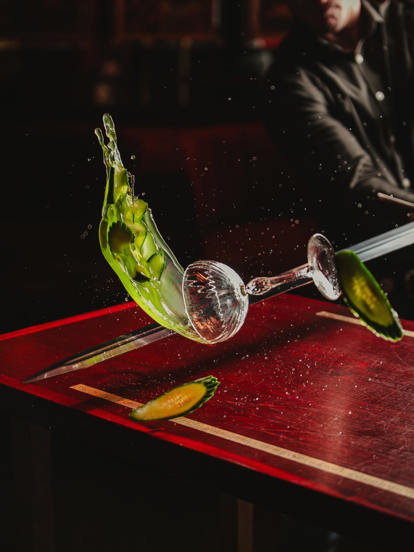 Green cocktail and glass flying mid-air, sliced by the sword at Jackson The Tailor