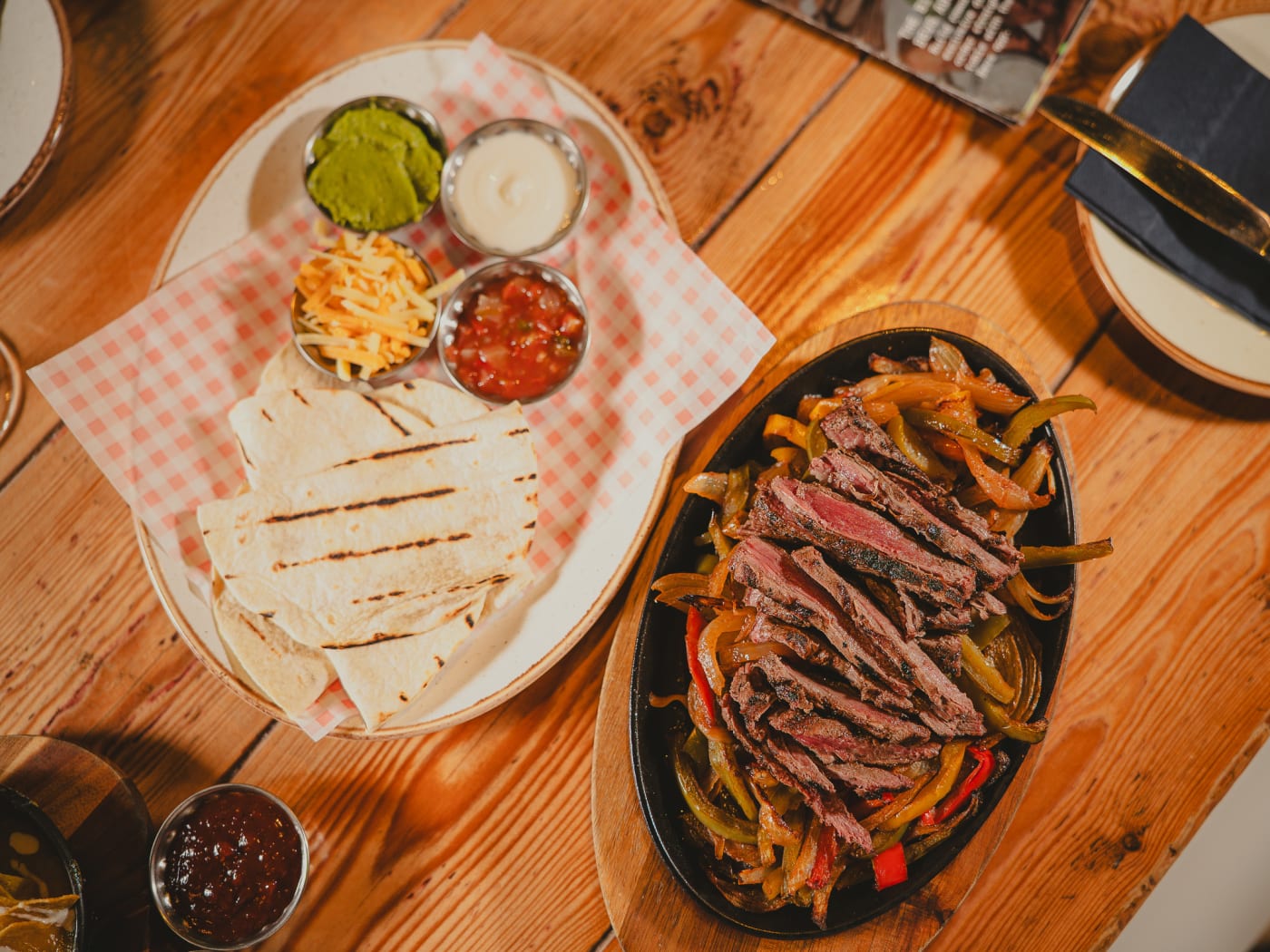 Overhead spread of steak fajitas, quesadillas and dips on a wooden table at Newsroom, Edinburgh
