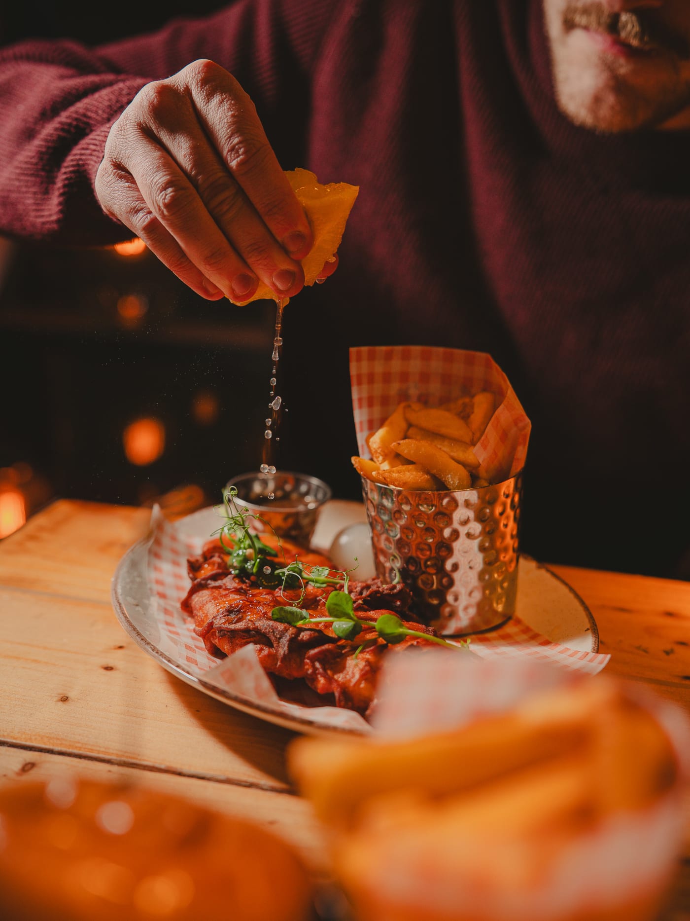 Hand dipping a fry into sauce over a platter of wings and chips at Newsroom, Edinburgh