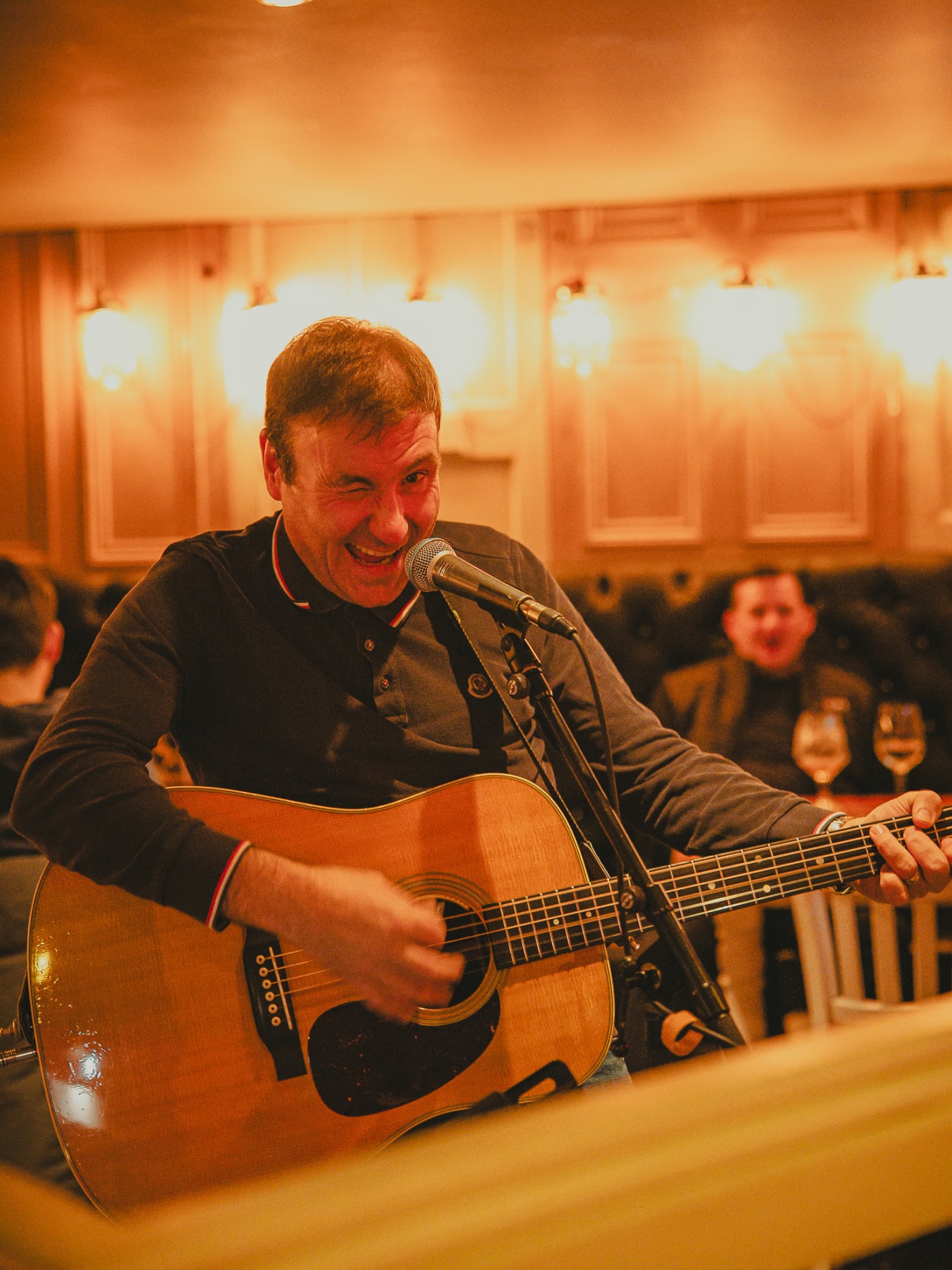 Live musician singing and playing acoustic guitar for the evening crowd at Newsroom, Edinburgh
