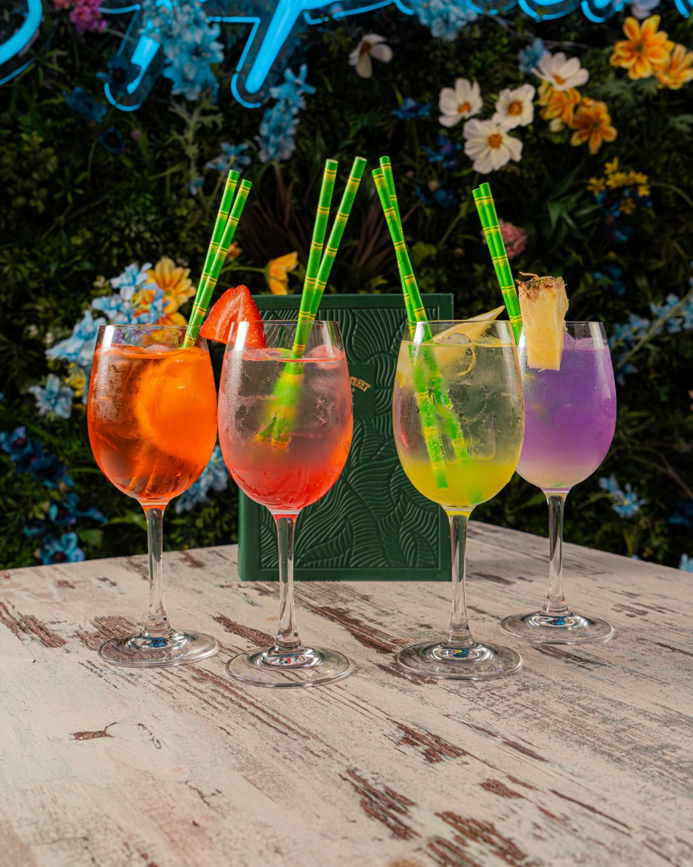 Line-up of colourful spritzes under the neon sign at Rose Street Garden, Edinburgh