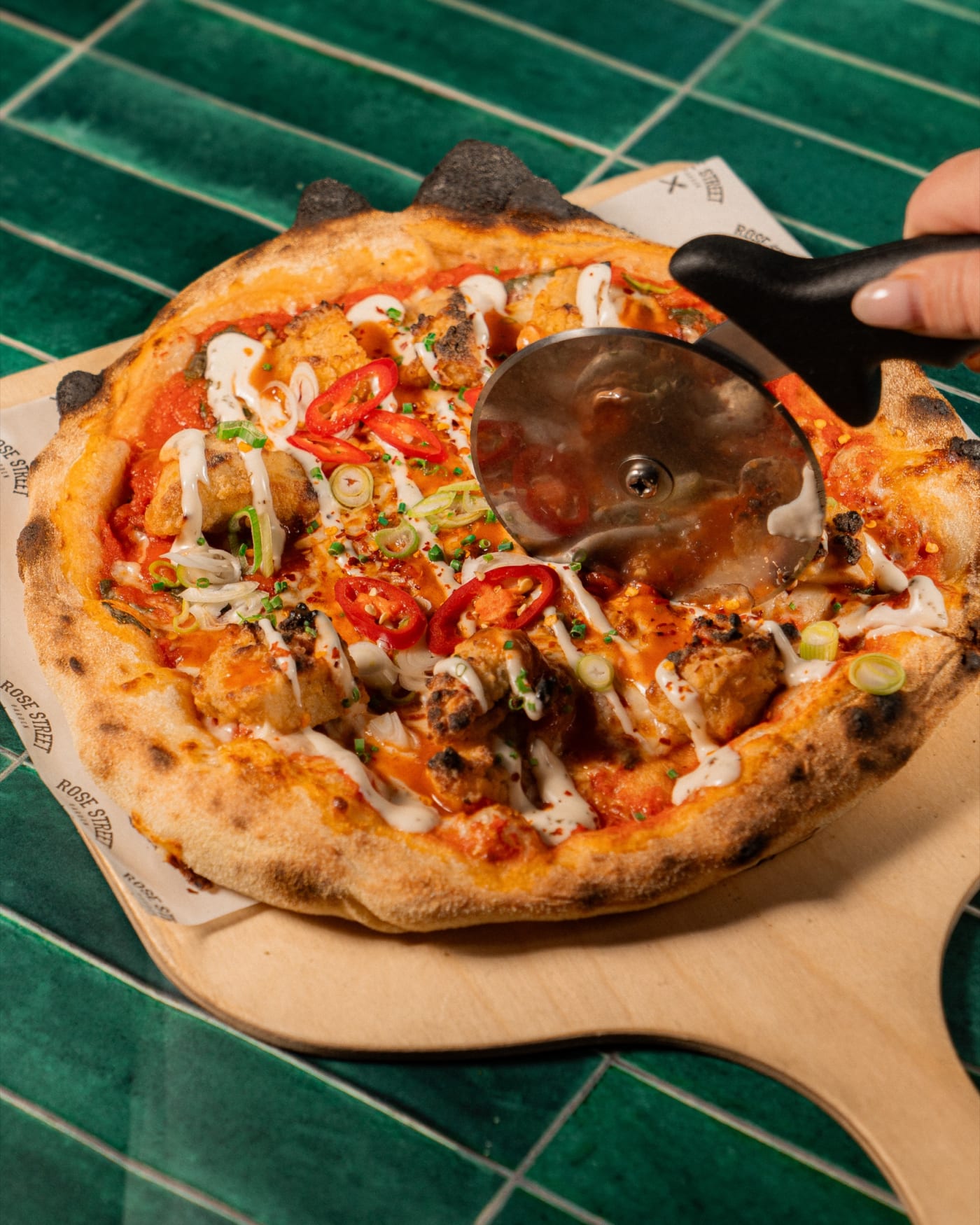 Slicing a wood-fired pizza on the green tiles at Rose Street Garden, Edinburgh