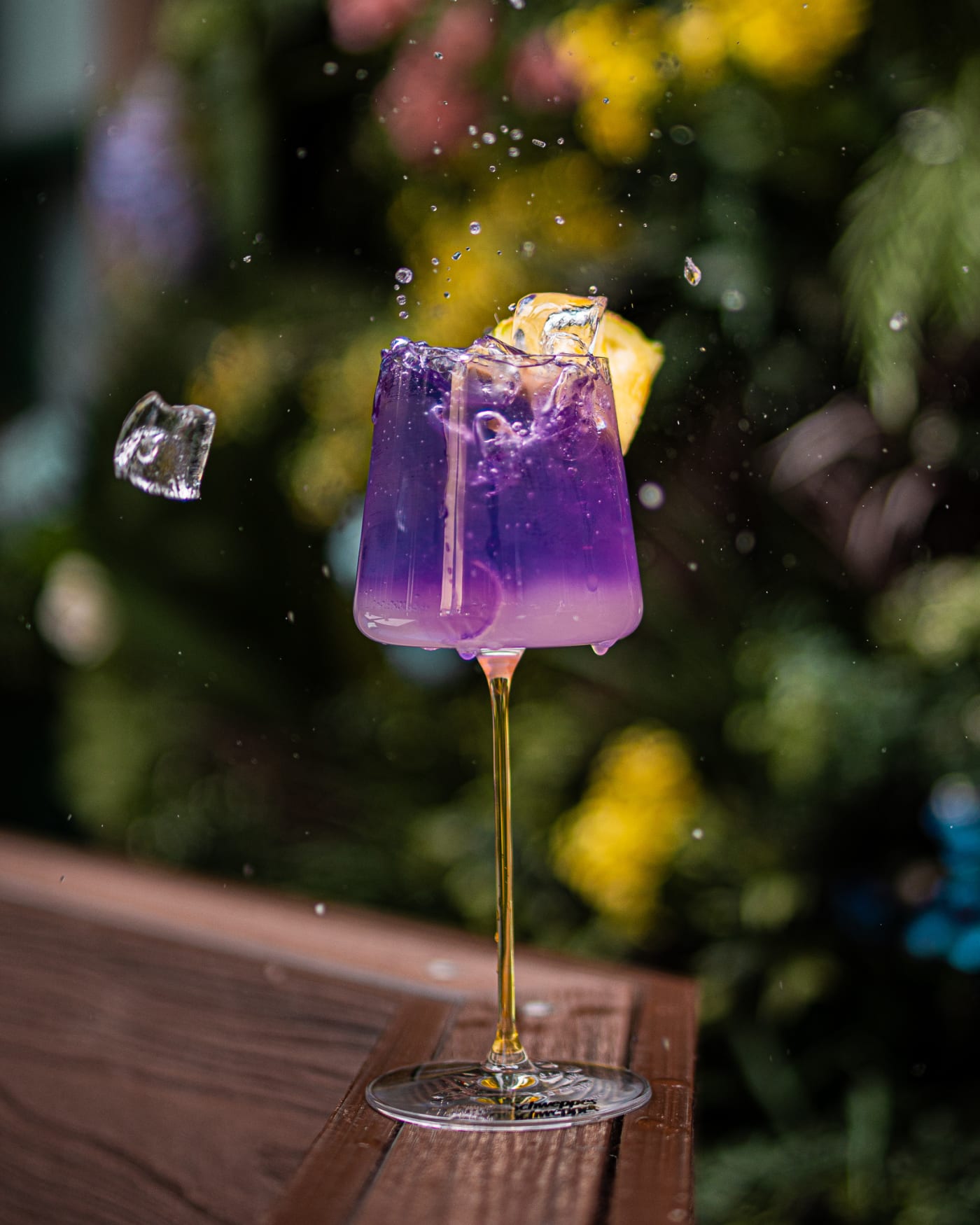 Syrup poured into a violet cocktail with ice mid-air at Rose Street Garden, Edinburgh