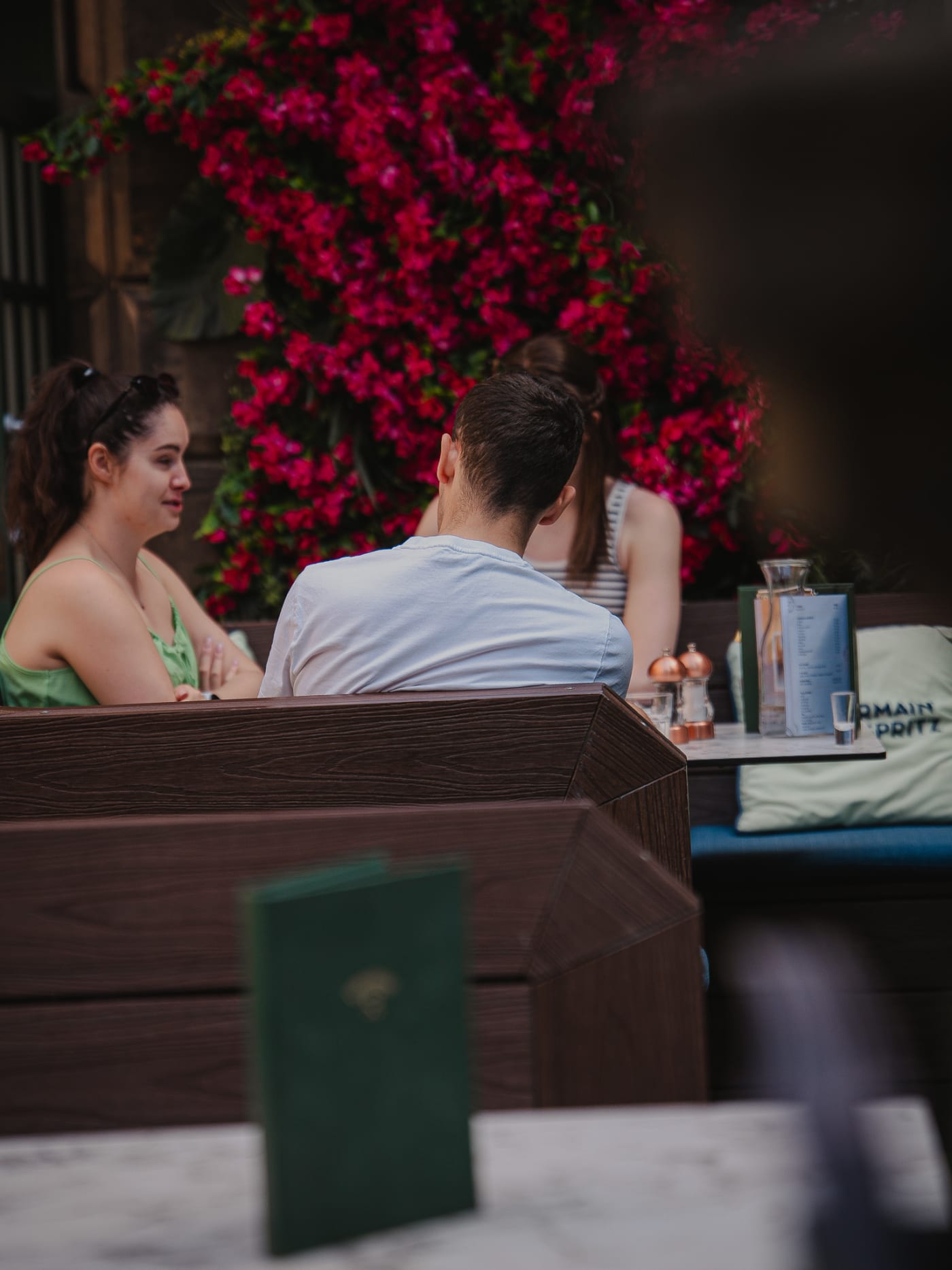 Friends chatting under the pink flower wall at Rose Street Garden, Edinburgh
