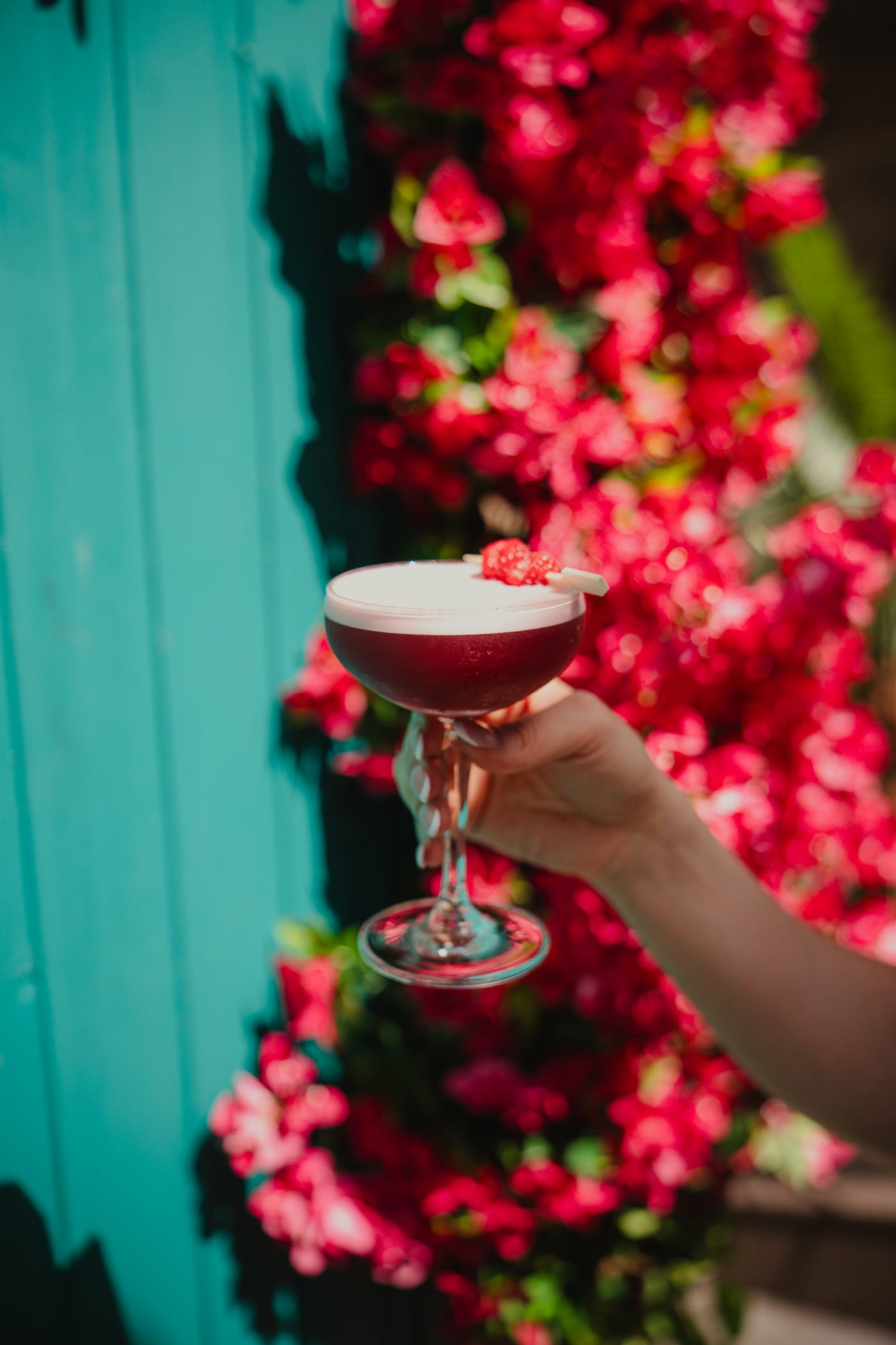 Raising a raspberry cocktail by the turquoise door and bougainvillea at Rose Street Garden, Edinburgh