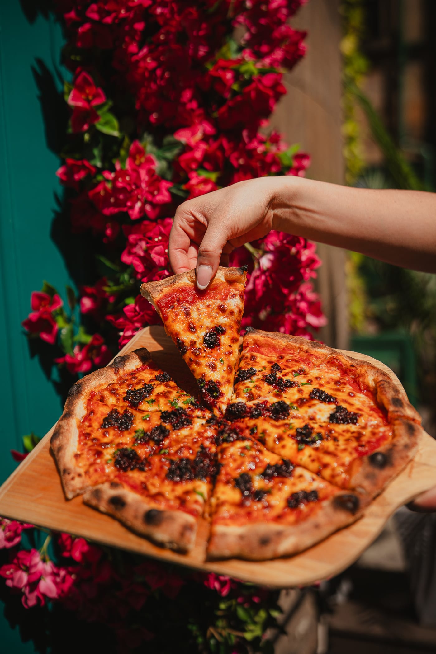 Pizza slice held against the bougainvillea at Rose Street Garden, Edinburgh