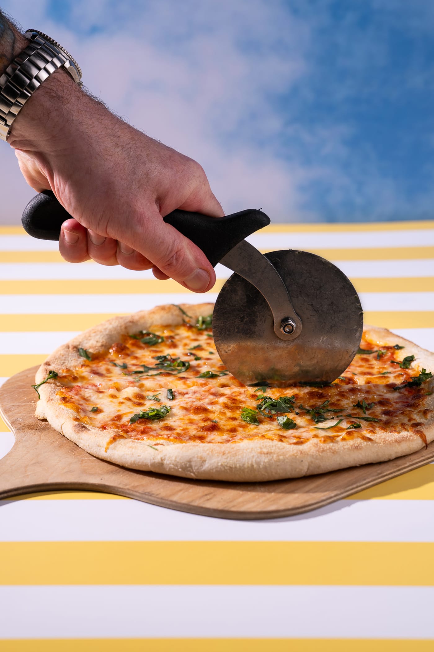 Cutting a garlic pizza against the sky backdrop at Rose Street Garden, Edinburgh