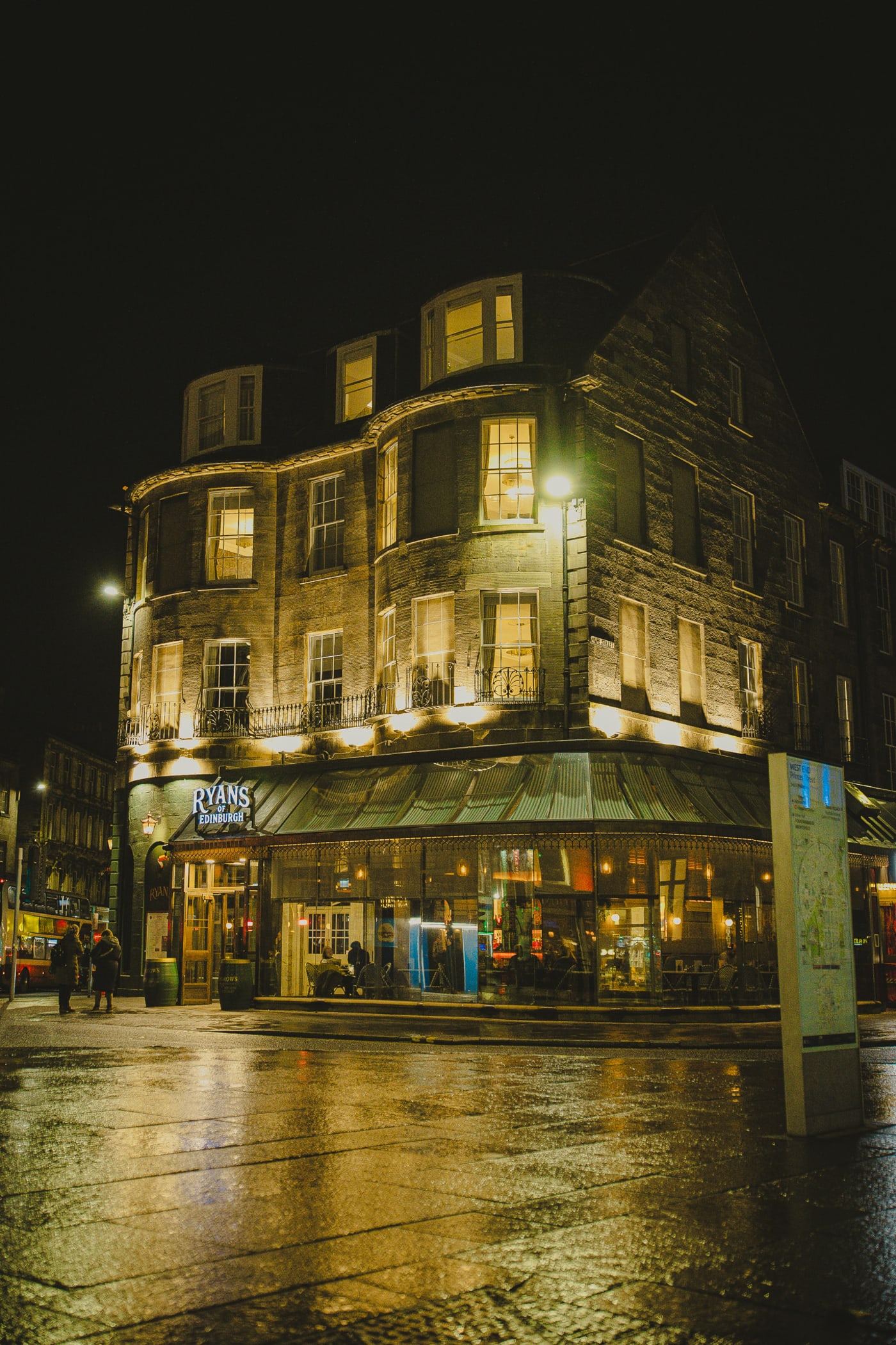 Ryan's of Edinburgh facade glowing at night in the rain