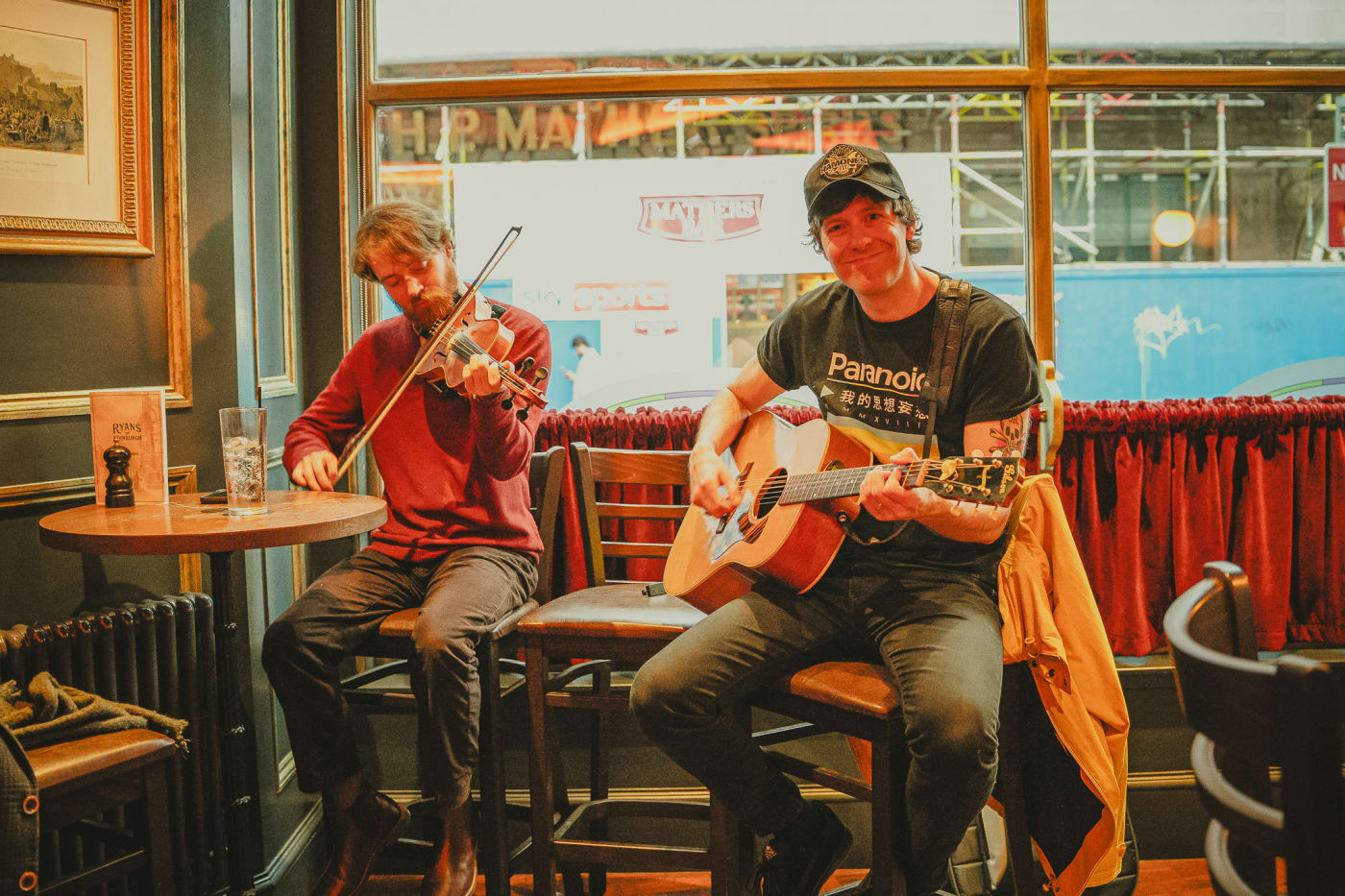 Folk duo on violin and guitar playing by the window at Ryan's of Edinburgh