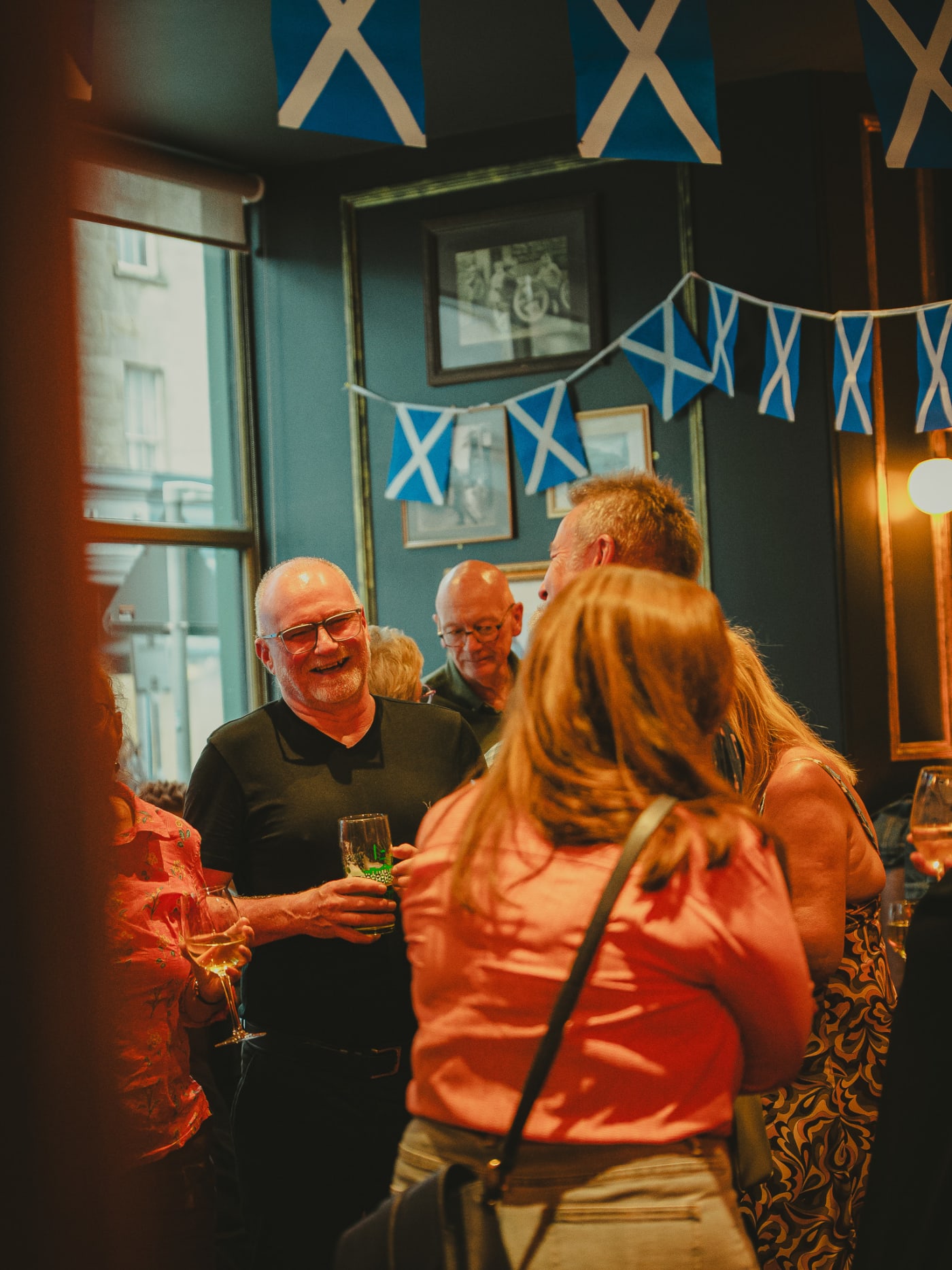 Friends with drinks under the window Saltires at Ryan's of Edinburgh