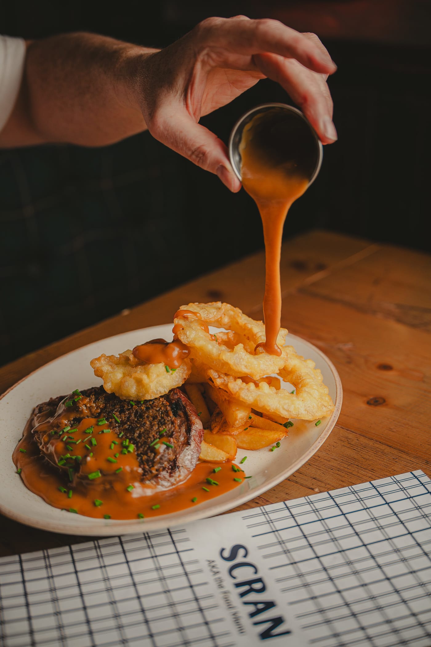 Sauce poured over steak and onion rings at The Piper's Rest