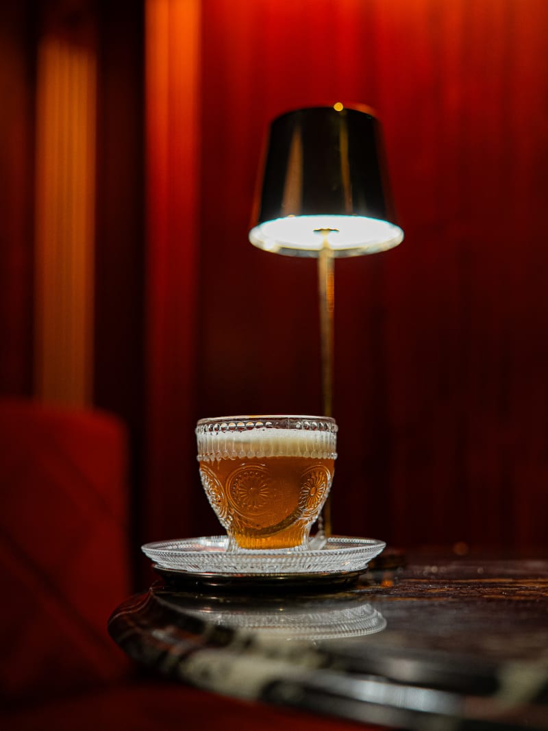 Red cocktail with a charred leaf garnish at Jackson The Tailor