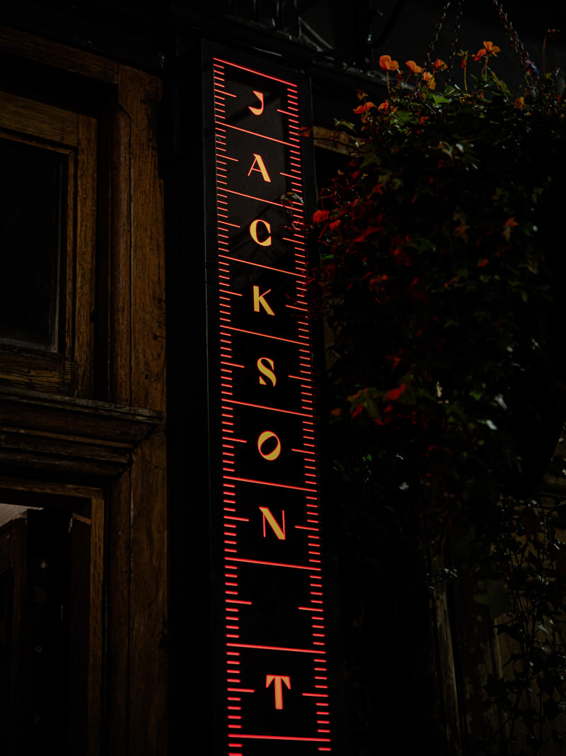 Jackson The Tailor neon sign glowing at night